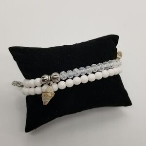 pair of white and clear stretch bracelets with shell charms
